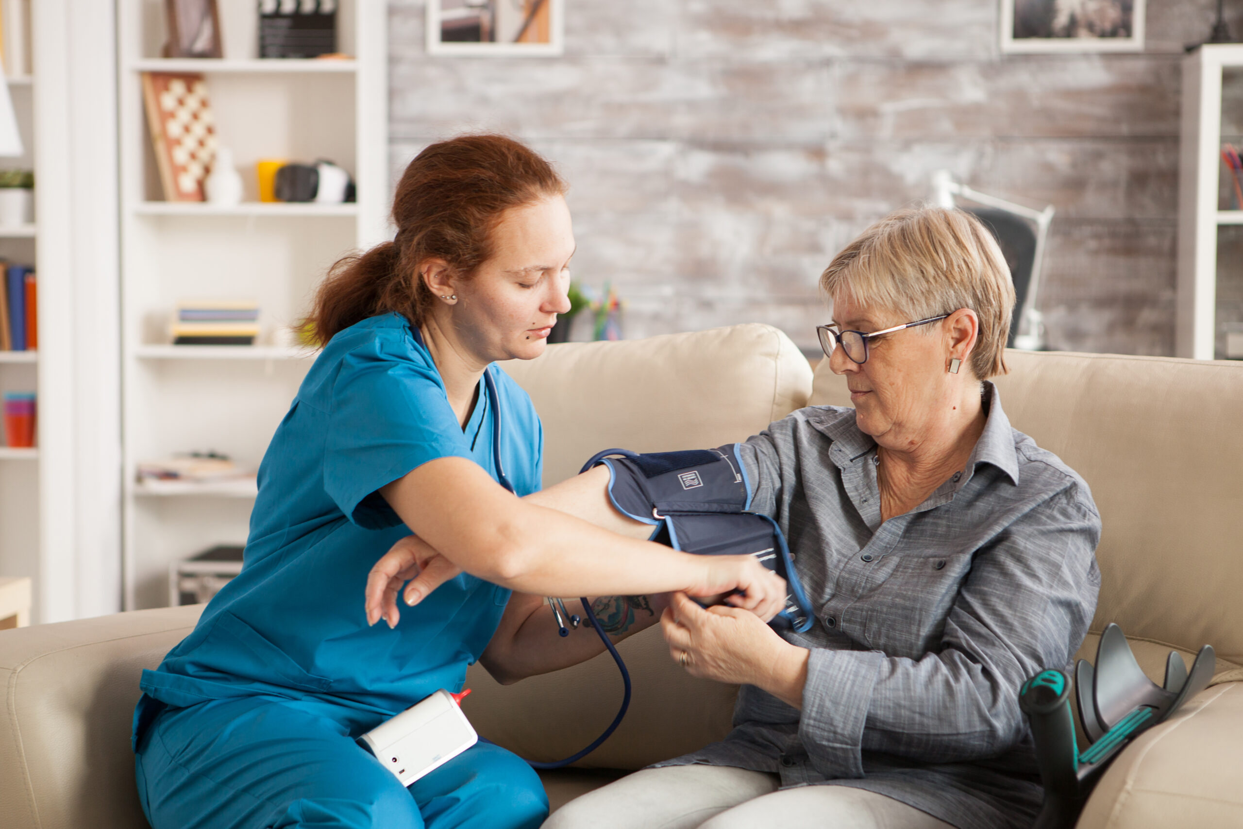 female nurse using digital blood pressure device senior woman nursing home